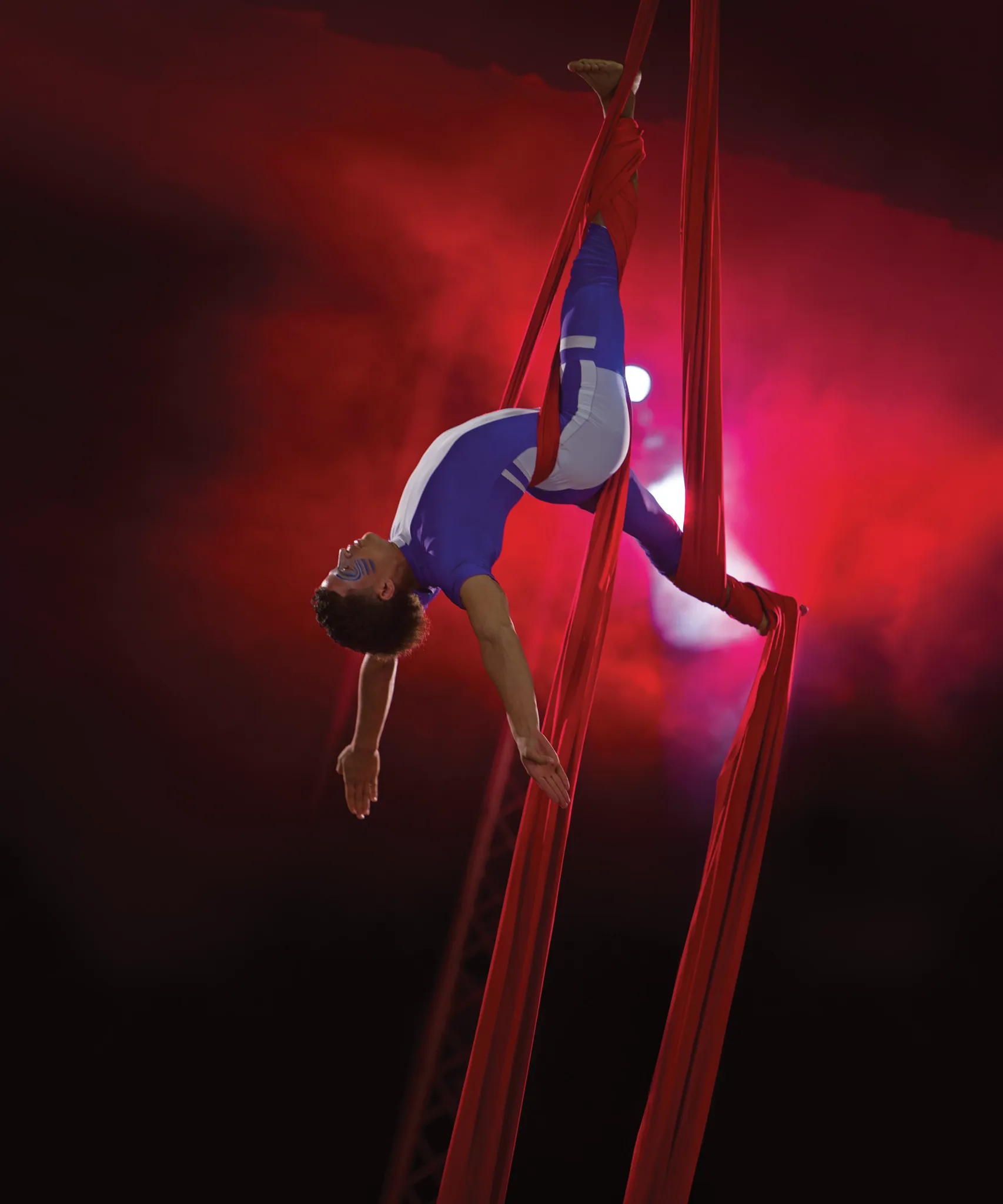 Aerial acrobat performing on red silks during an evening show at Dreams Royal Beach Punta Cana.