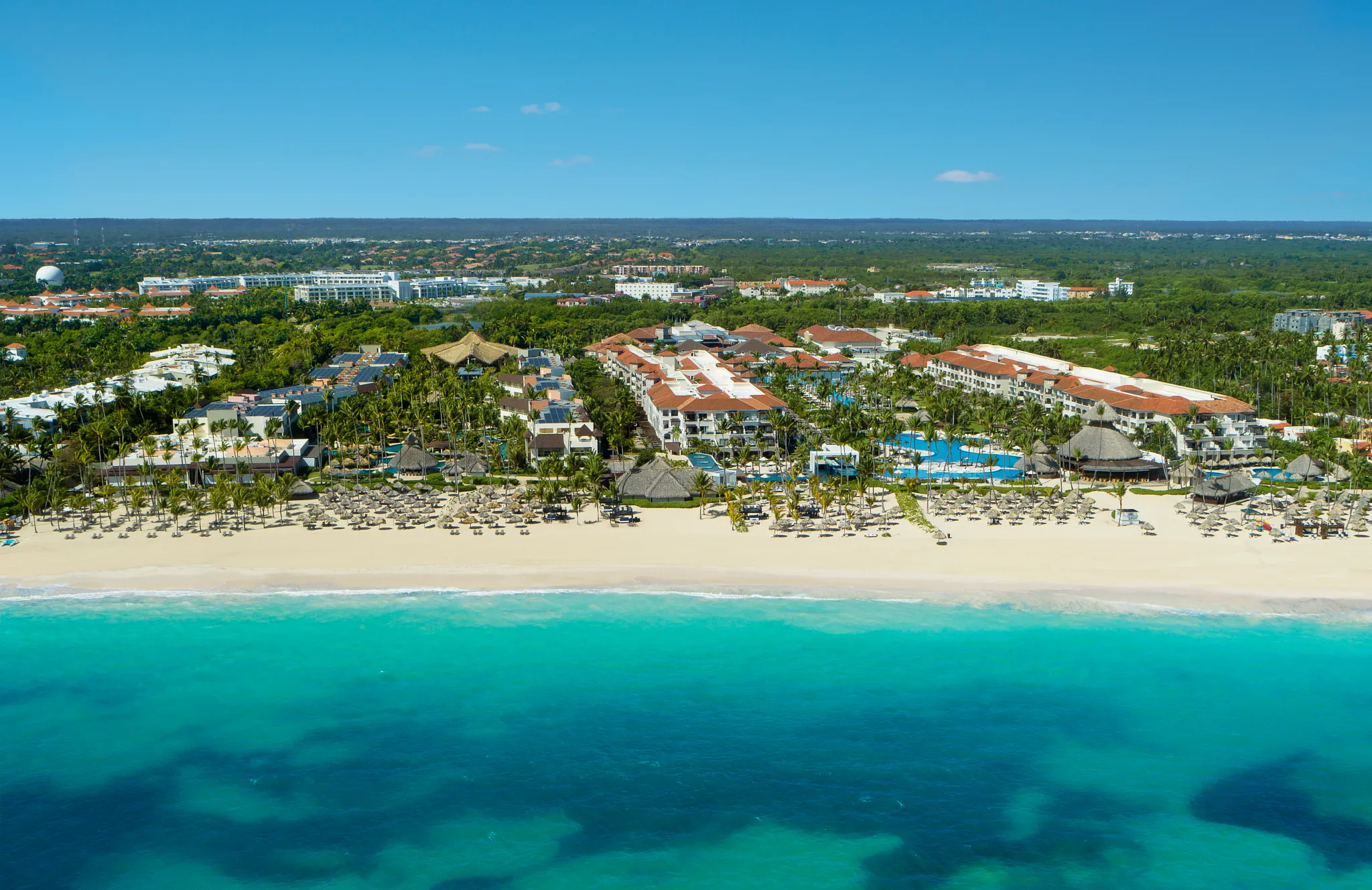 Aerial view of Dreams Royal Beach Punta Cana showcasing beachfront pools, palm-lined grounds, and white sand beach along the Caribbean Sea.