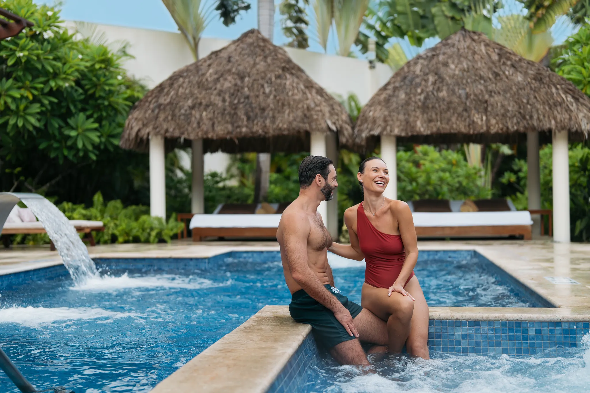 Couple enjoying spa pool with waterfalls and cabanas at Dreams Royal Beach Punta Cana.