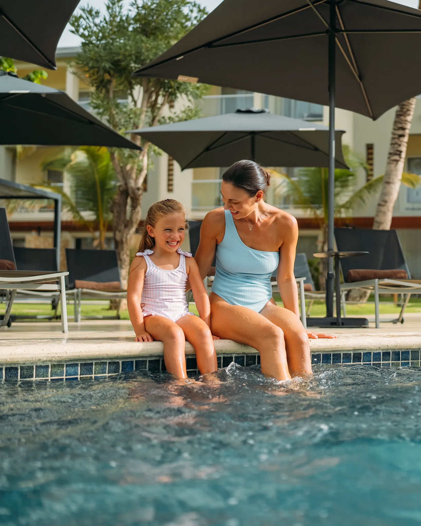 Mother and daughter relaxing at a poolside area at Dreams Royal Beach Punta Cana, enjoying a family-friendly resort experience.