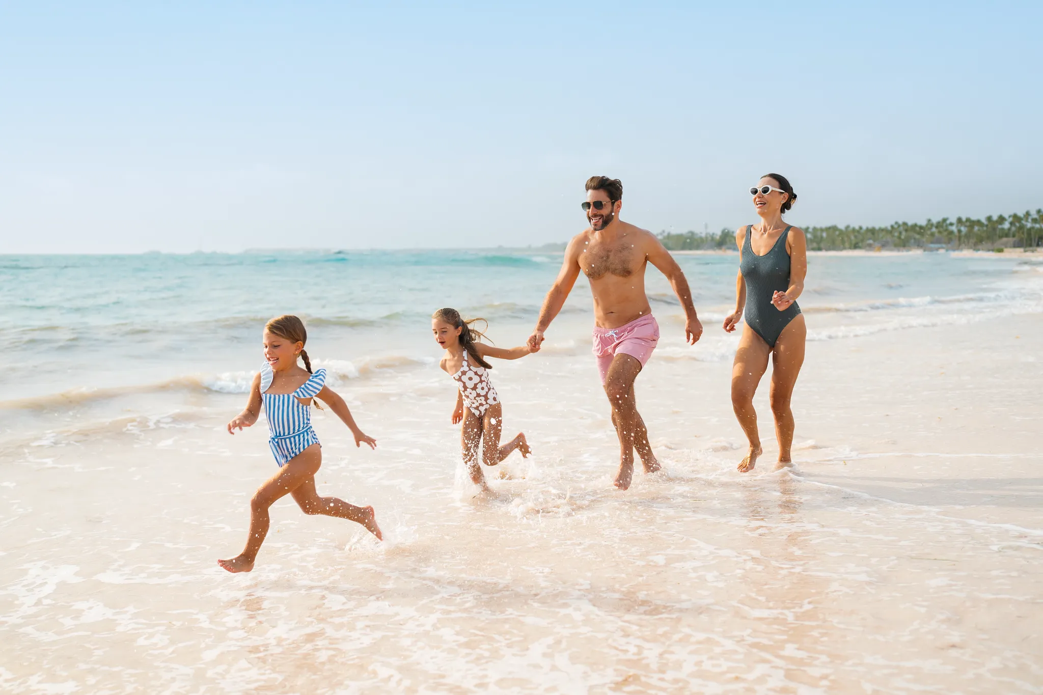 Father and daughter playing together on a sandy beach at Dreams Royal Beach Punta Cana during sunset.