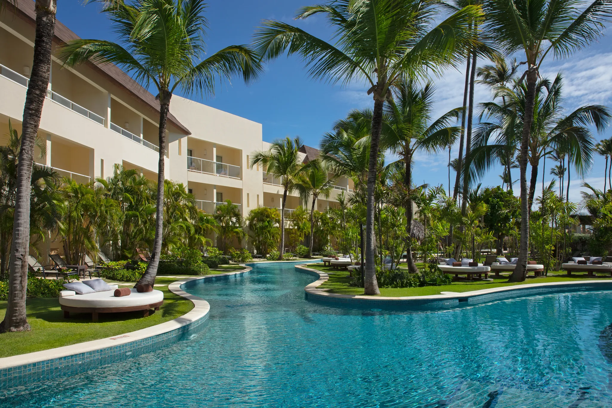 Pool courtyard surrounded by tropical plants and resort buildings at Dreams Royal Beach Punta Cana.