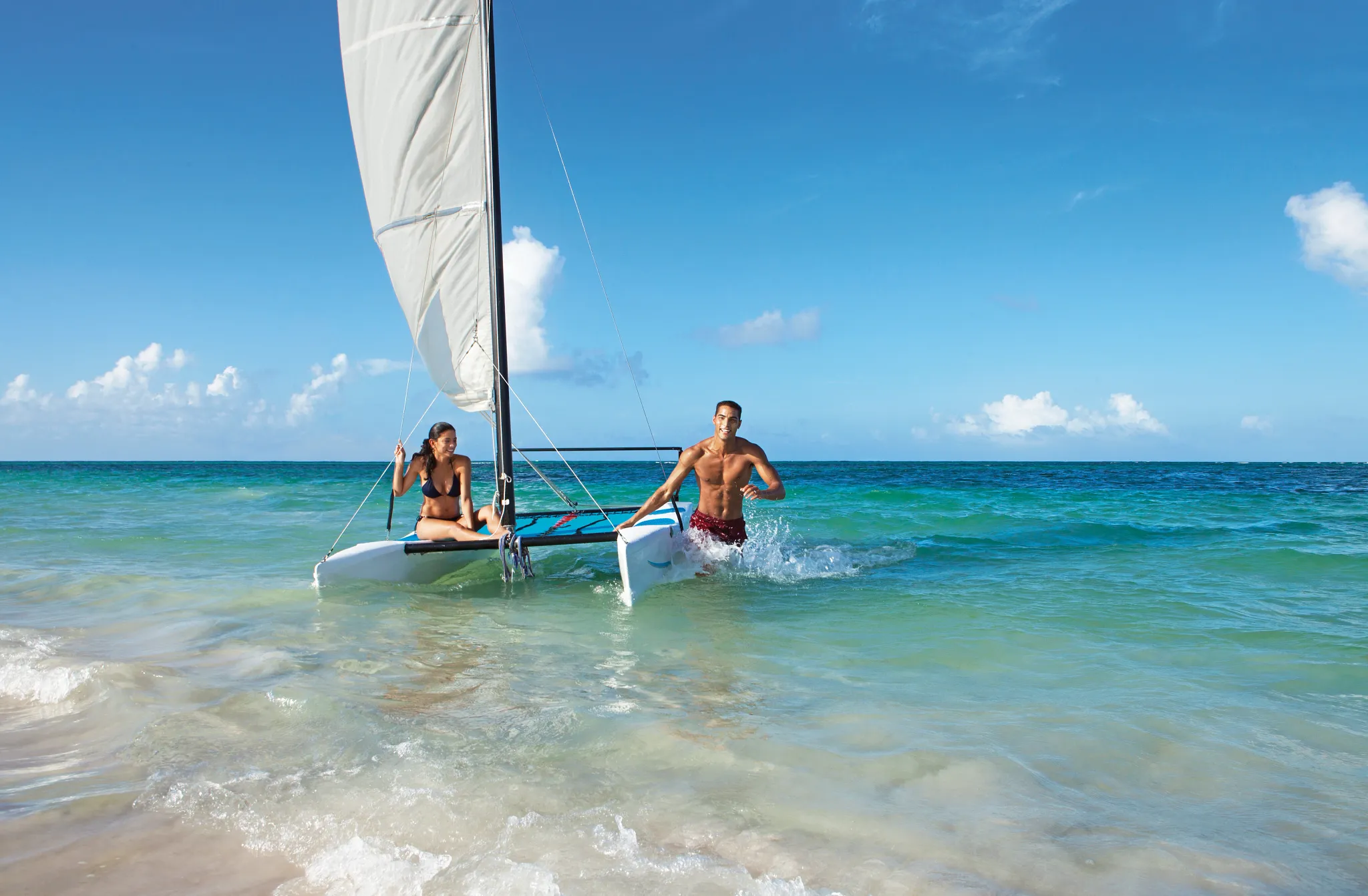 Couple sailing a Hobie Cat catamaran in clear Caribbean waters at Dreams Royal Beach Punta Cana.