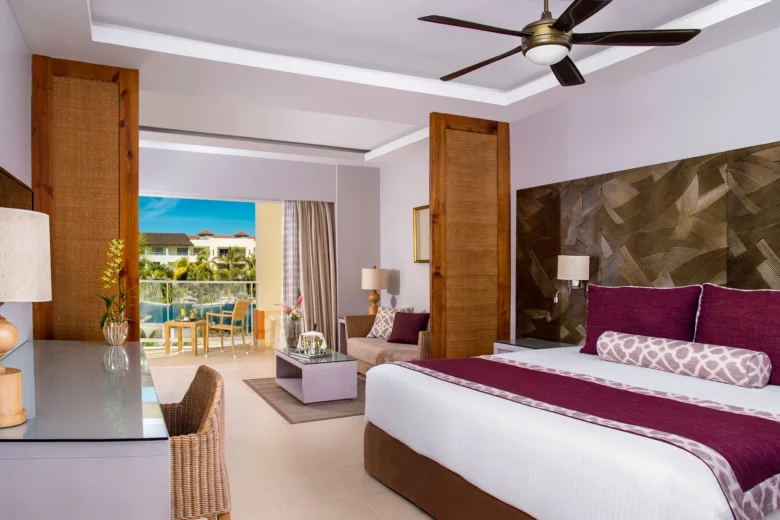 Preferred Club Deluxe Partial Ocean View room with king bed and balcony overlooking pool and ocean at Dreams Royal Beach Punta Cana.