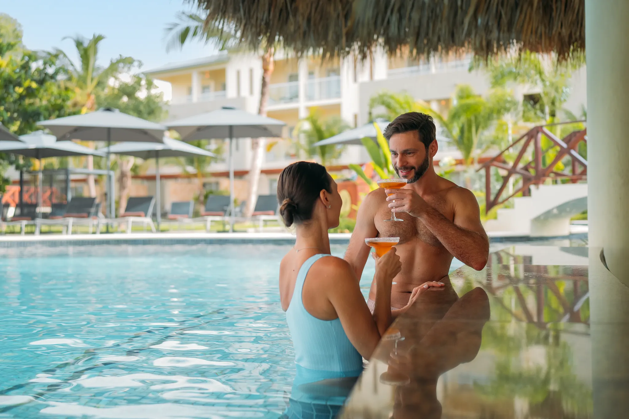 Couple enjoying cocktails at a swim-up bar in Dreams Royal Beach Punta Cana pool.